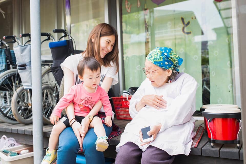 a japanese family of a baby, his mother, and an elderly lady sitting on a bench