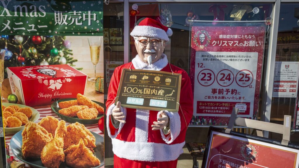 Christmas-ified Colonel Sanders holding deals for the holiday season.